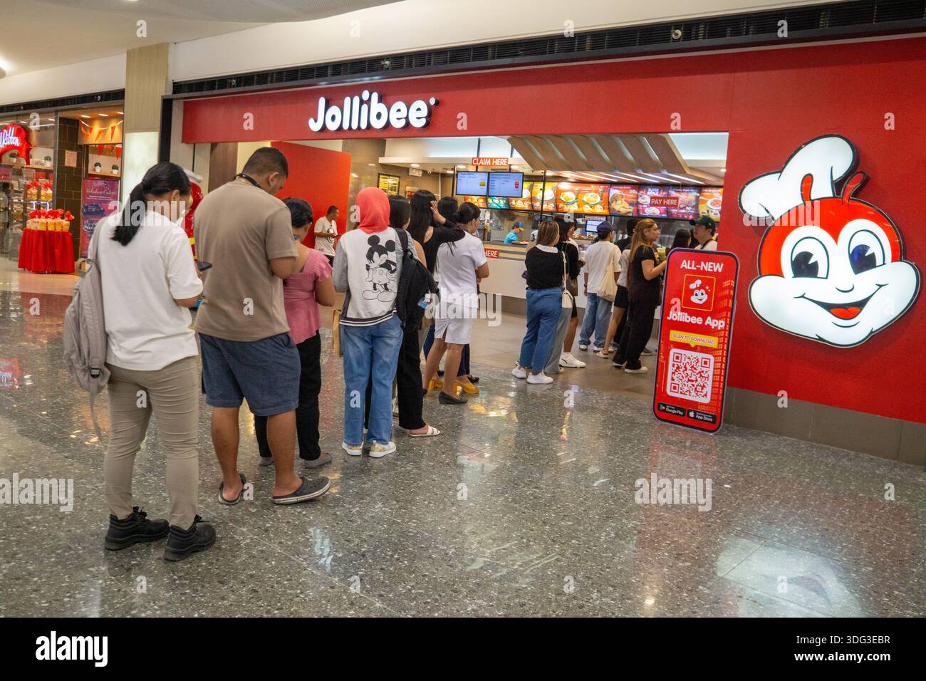 Les clients font la queue dans un restaurant Jollibee situé dans un centre commercial aux Philippines, mettant en évidence la demande de restauration rapide, la culture de consommation et la vie urbaine. Banque D'Images