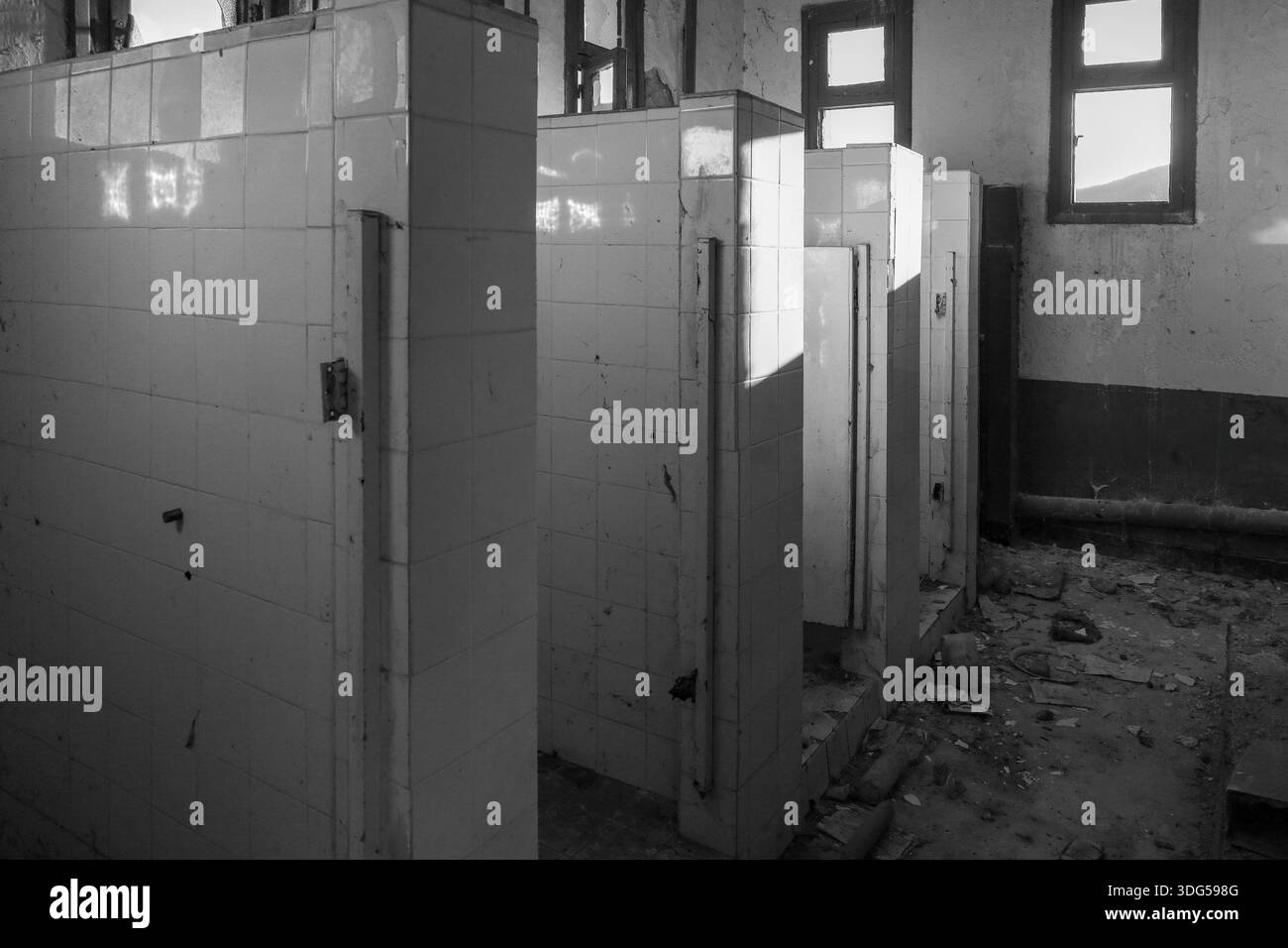 Photo en noir et blanc capturant la décadence urbaine dans des toilettes en ruine, évoquant les thèmes du silence, du temps perdu et du vide envoûtant. Banque D'Images