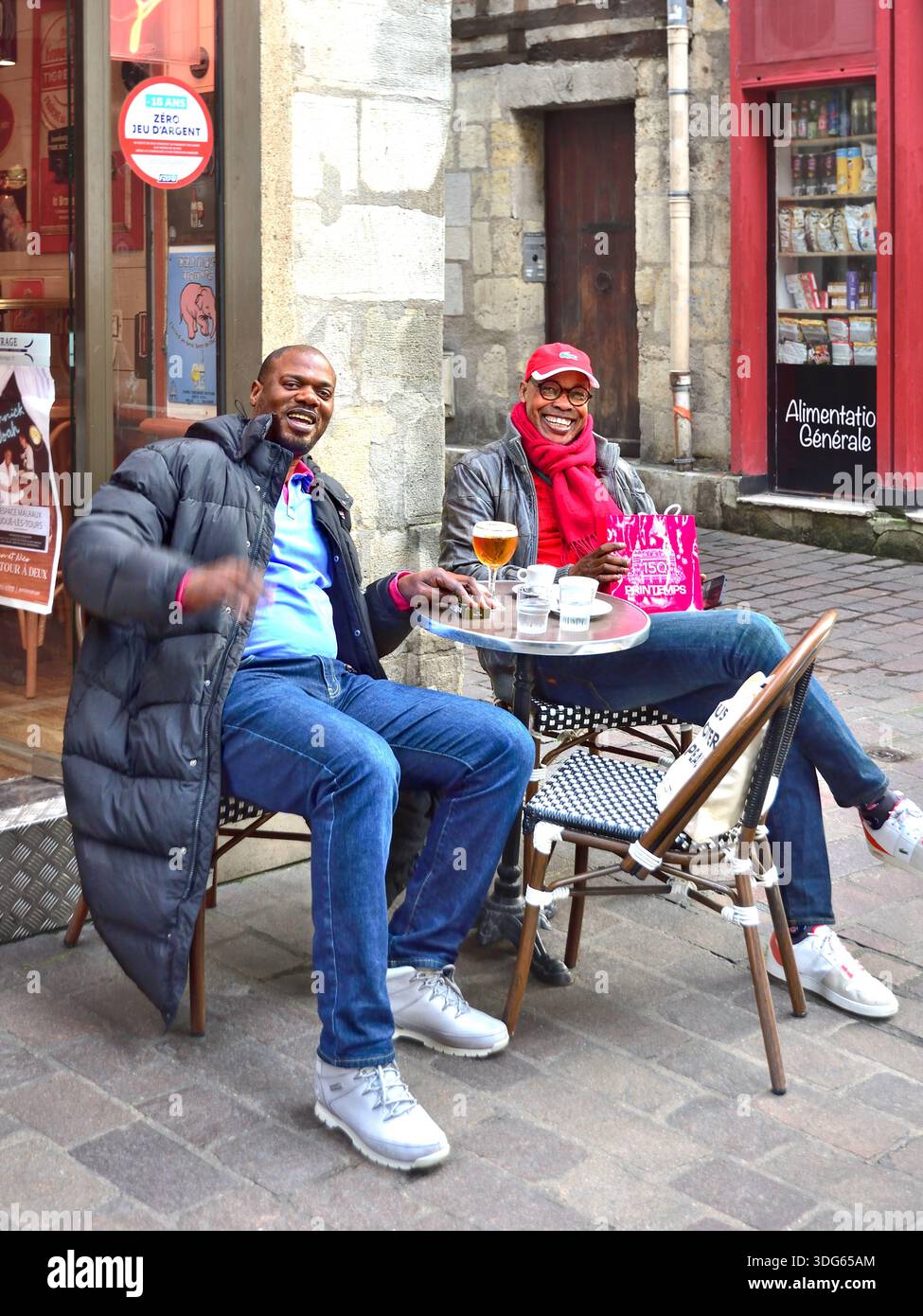 Deux hommes noirs français africains à une table de café en plein air posant pour une photographie - Tours, Indre-et-Loire (37), France. Banque D'Images