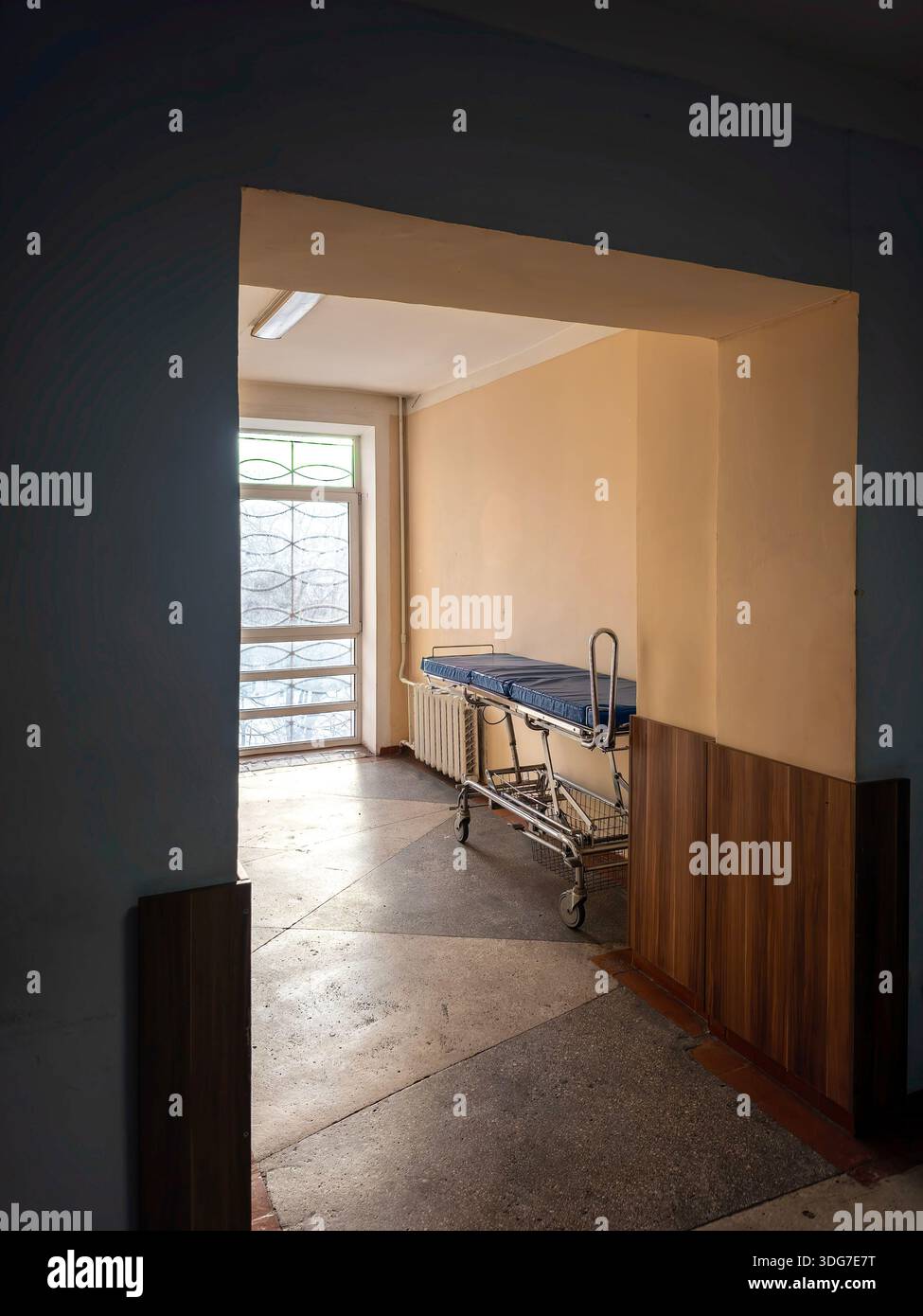 Kiev, Ukraine – 11 novembre 2025 : une vieille civière médicale en métal se tient dans un coin sombre d’un hôpital public délabré. Intérieur minable et manque de mode Banque D'Images