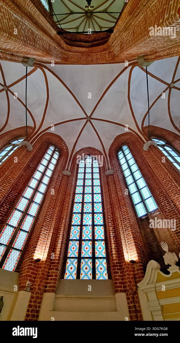 Intérieur gothique de l'église Saint-Pierre avec des arcs pointus, des voûtes nervurées et des vitraux avec des motifs géométriques complexes. Riga, Lettonie Banque D'Images