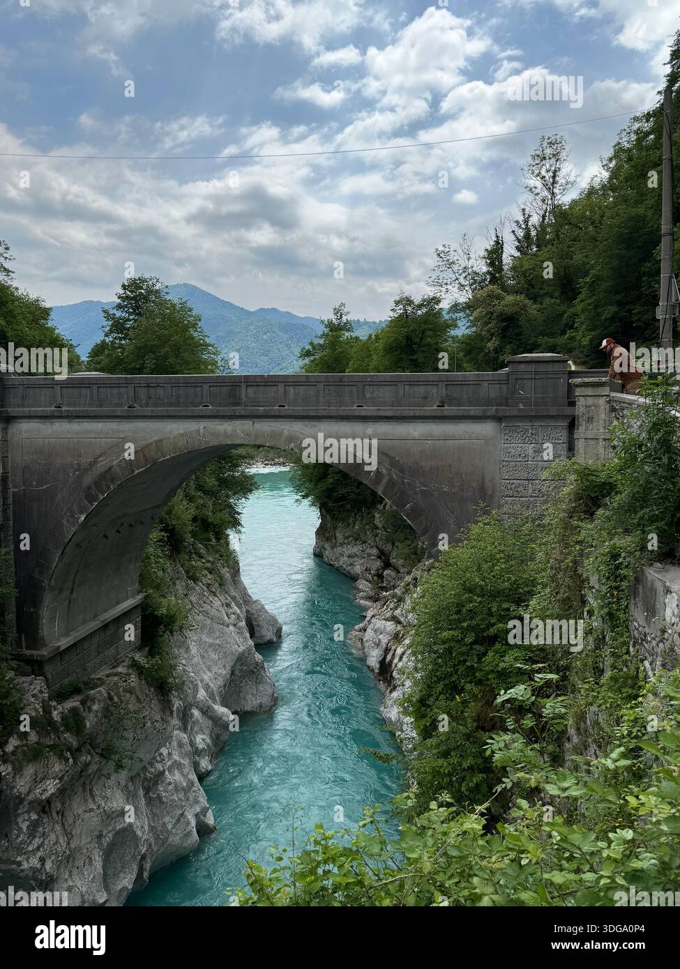 Un pont de pierre historique enjambe une gorge fluviale turquoise dans le paysage alpin de Slovénie, mêlant beauté naturelle et ingénierie intemporelle - Image de stock capturée avec un smartphone