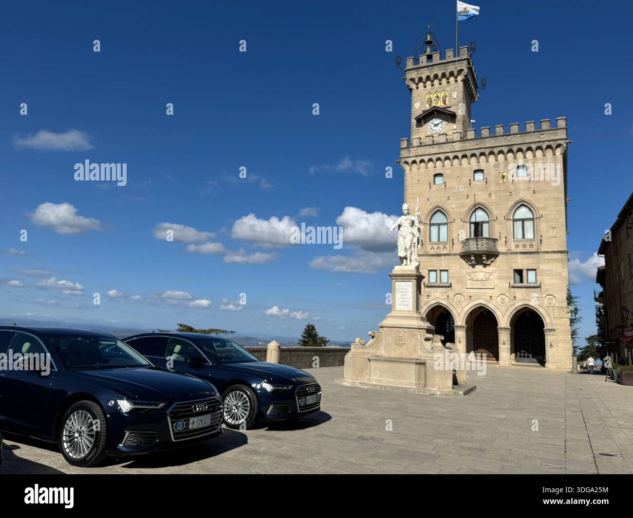 Palazzo Pubblico à Saint-Marin avec statue et voitures garées sous le ciel bleu sur la place historique de la ville - Image de stock capturée avec un smartphone