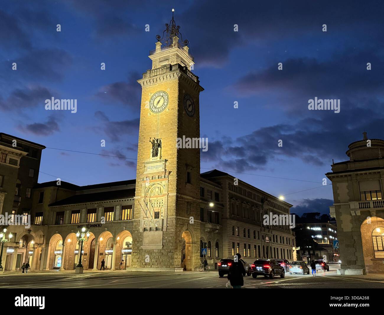 Tour de l'horloge et bâtiments historiques à Bergame, Italie, illuminés au crépuscule, avec le trafic de la ville et le ciel bleu spectaculaire du soir - Image de stock capturée avec un smartphone