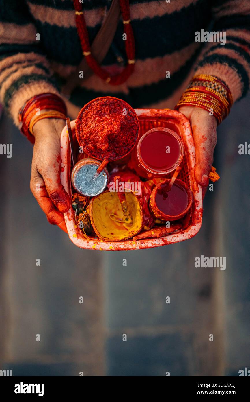 Vue des mains tenant un plateau avec des poudres et des liquides colorés vibrants, une célébration de la culture et de la tradition, Himalaya, Annapurna, Népal. Banque D'Images
