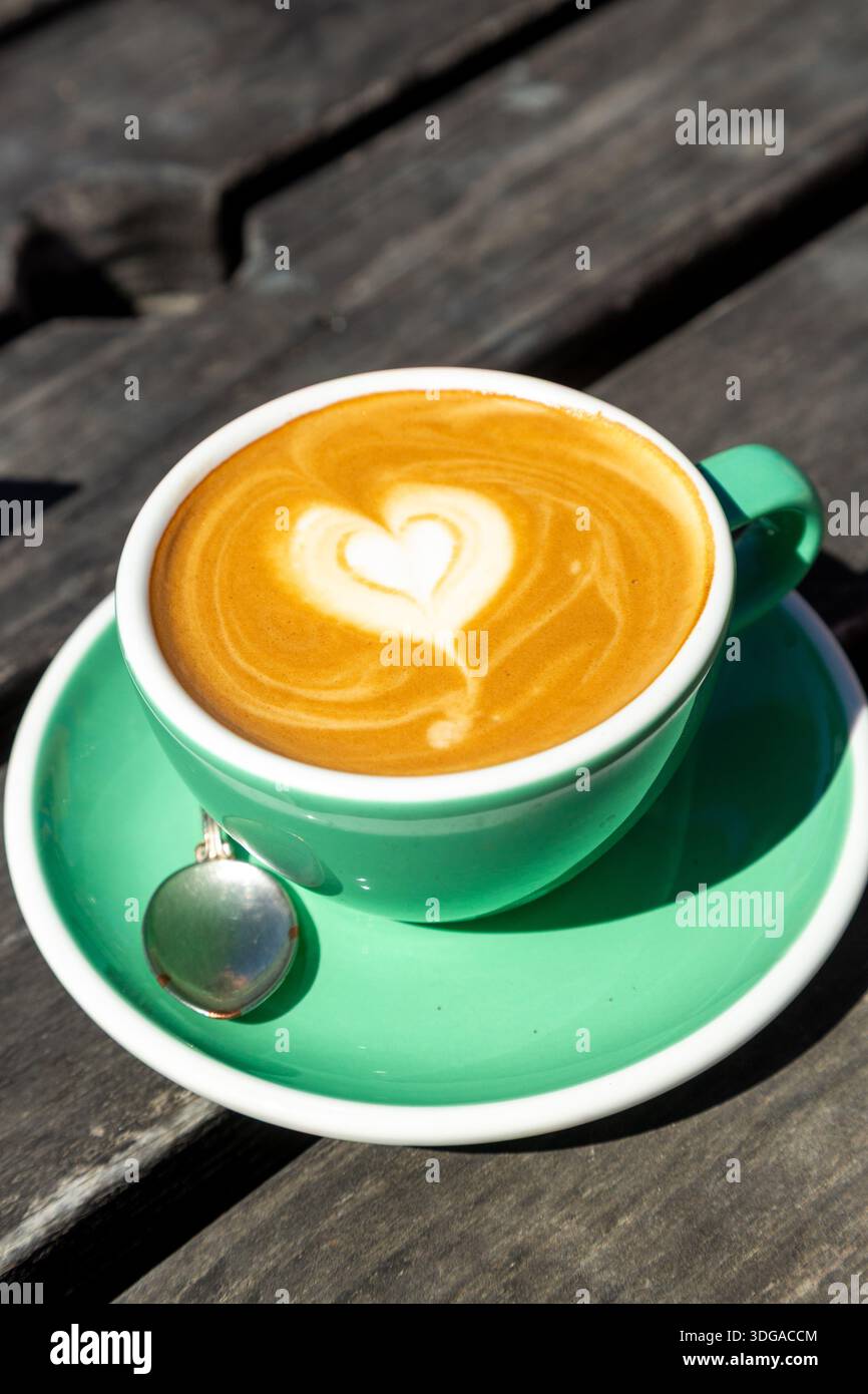 Une tasse de café avec latte art en forme de coeur servi dans une tasse en céramique verte et une soucoupe Banque D'Images