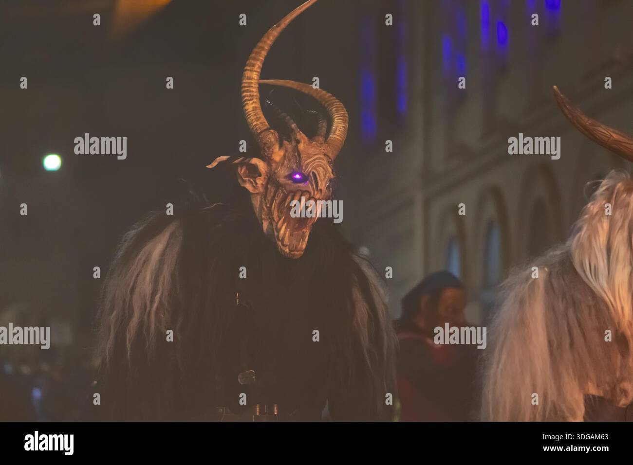 Krampus avec de grandes cornes courbées et des yeux brillants se tient parmi les participants à la procession Banque D'Images
