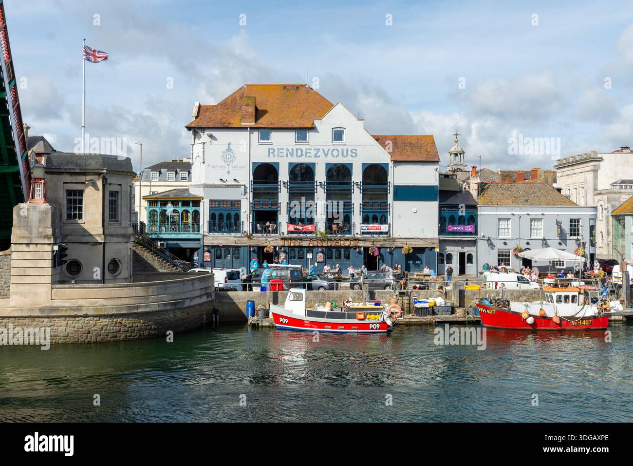Weymouth, Royaume-Uni - 5 septembre 2025 : drapeau de l'Union Jack survolant le Control Pavilion sur le Town Bridge à côté de bateaux de pêche amarrés dans le port. Banque D'Images