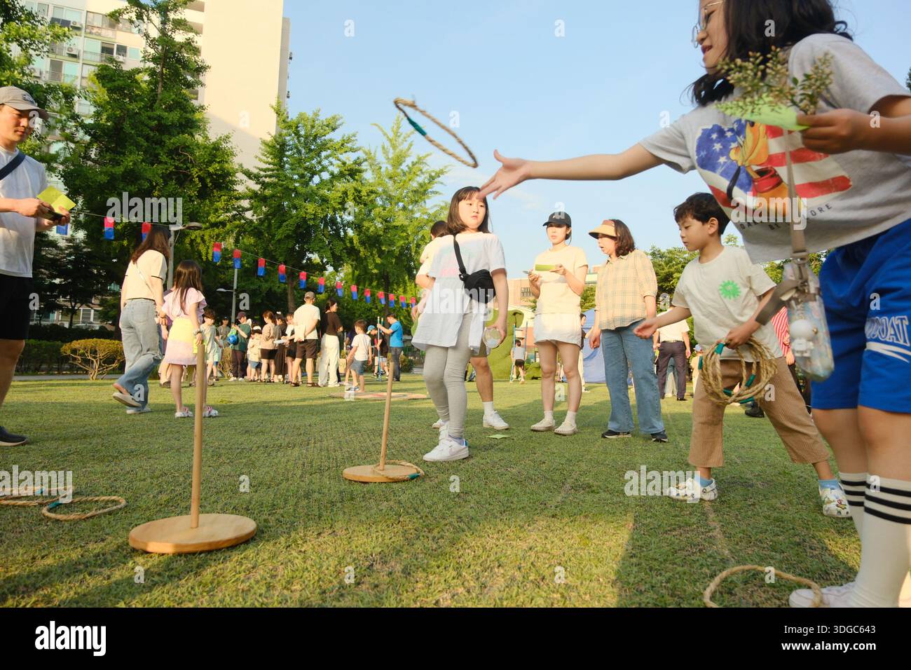 Séoul, Corée du Sud : les enfants jouent au jeu traditionnel de lancer de bague lors du festival d'été communautaire dans le parc de la ville Banque D'Images