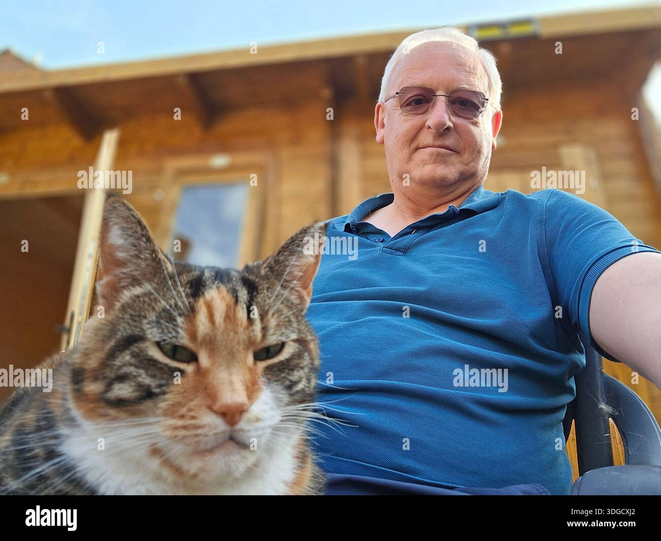 Homme et chat assis près d'un hangar Banque D'Images