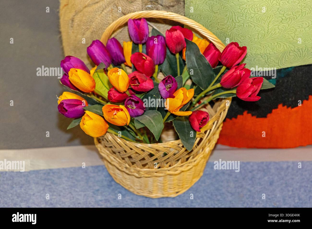 Bouquet de tulipes artificielles colorées dans un panier tissé Vicker Banque D'Images