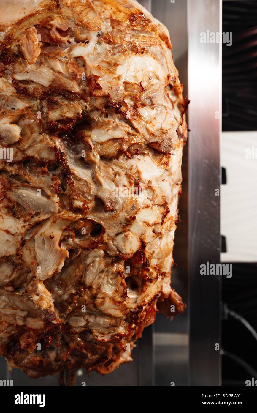 Une rôtisserie verticale fait tourner des couches de viande assaisonnée pour le shawarma. Banque D'Images