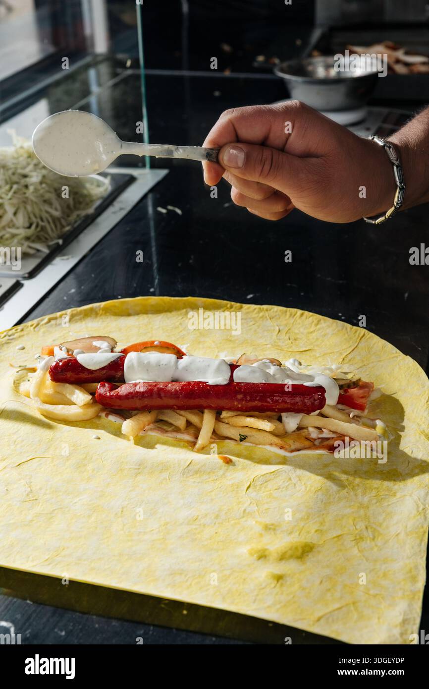 Chef versant une sauce blanche sur Doner Kebab Banque D'Images