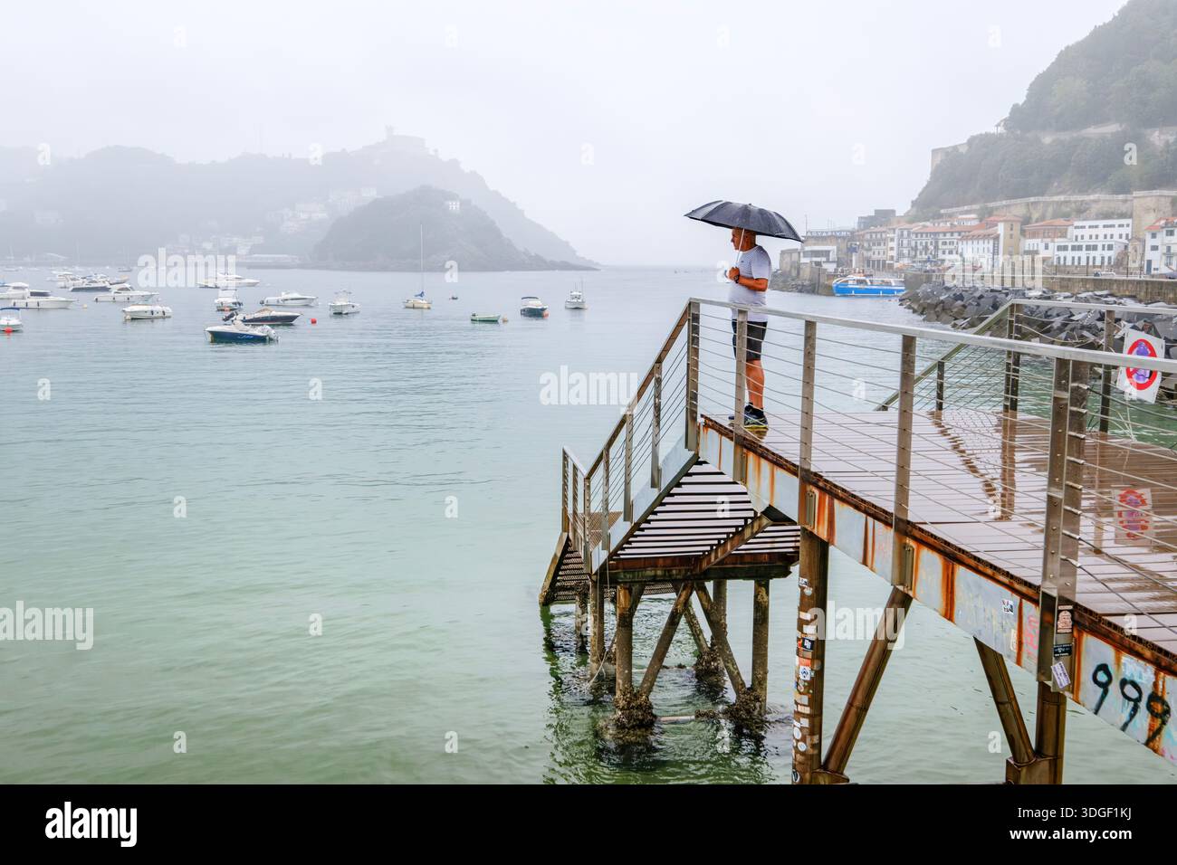 Homme avec un parapluie regardant la mer un jour de pluie, la baie de la Concha, San Sebastian Banque D'Images