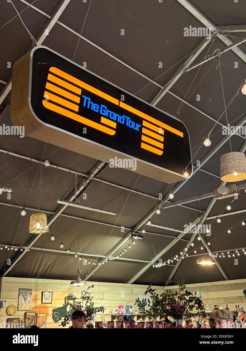 Panneau lumineux « The Grand Tour » accroché à l’intérieur d’un espace intérieur de style événementiel, faisant référence à la populaire série télévisée automobile britannique. - Image de stock capturée avec un smartphone