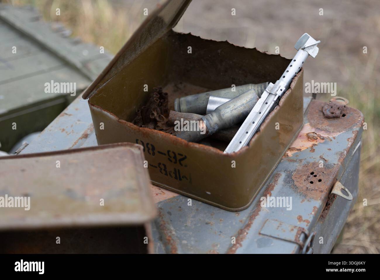 L'invention concerne une boîte de munitions rouillée ouverte remplie d'enveloppes usées, de maillons de courroie et d'un stabilisateur d'aileron arrière RPG-7. Jetés sur un champ de bataille, ces restes s Banque D'Images