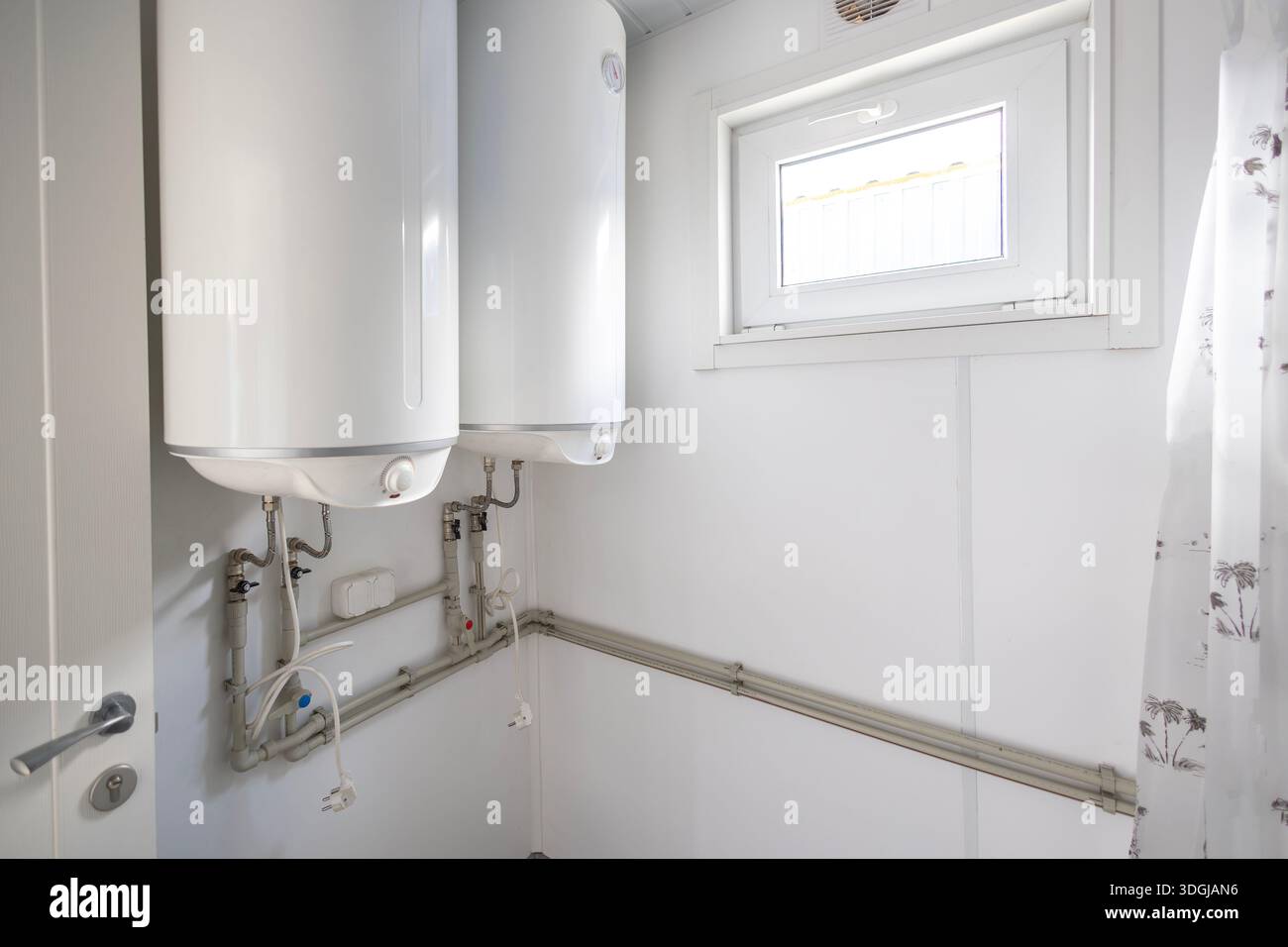 Deux grands chauffe-eau électriques sont montés sur le mur d'une buanderie fonctionnelle ou d'une salle de bains. Cette configuration assure une eau chaude suffisante pour un fac partagé Banque D'Images