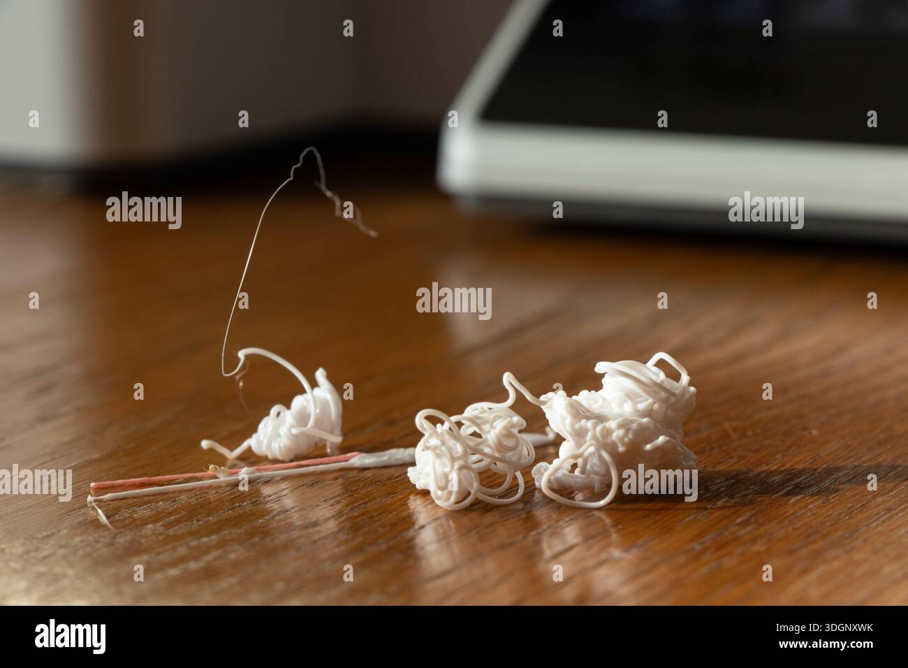 Résidus de plastique provenant de l'impression 3D sur une table en bois, brins et amas de filaments, déchets de production, flux de travail, consommation de matières premières et sortie de l'imprimante Banque D'Images