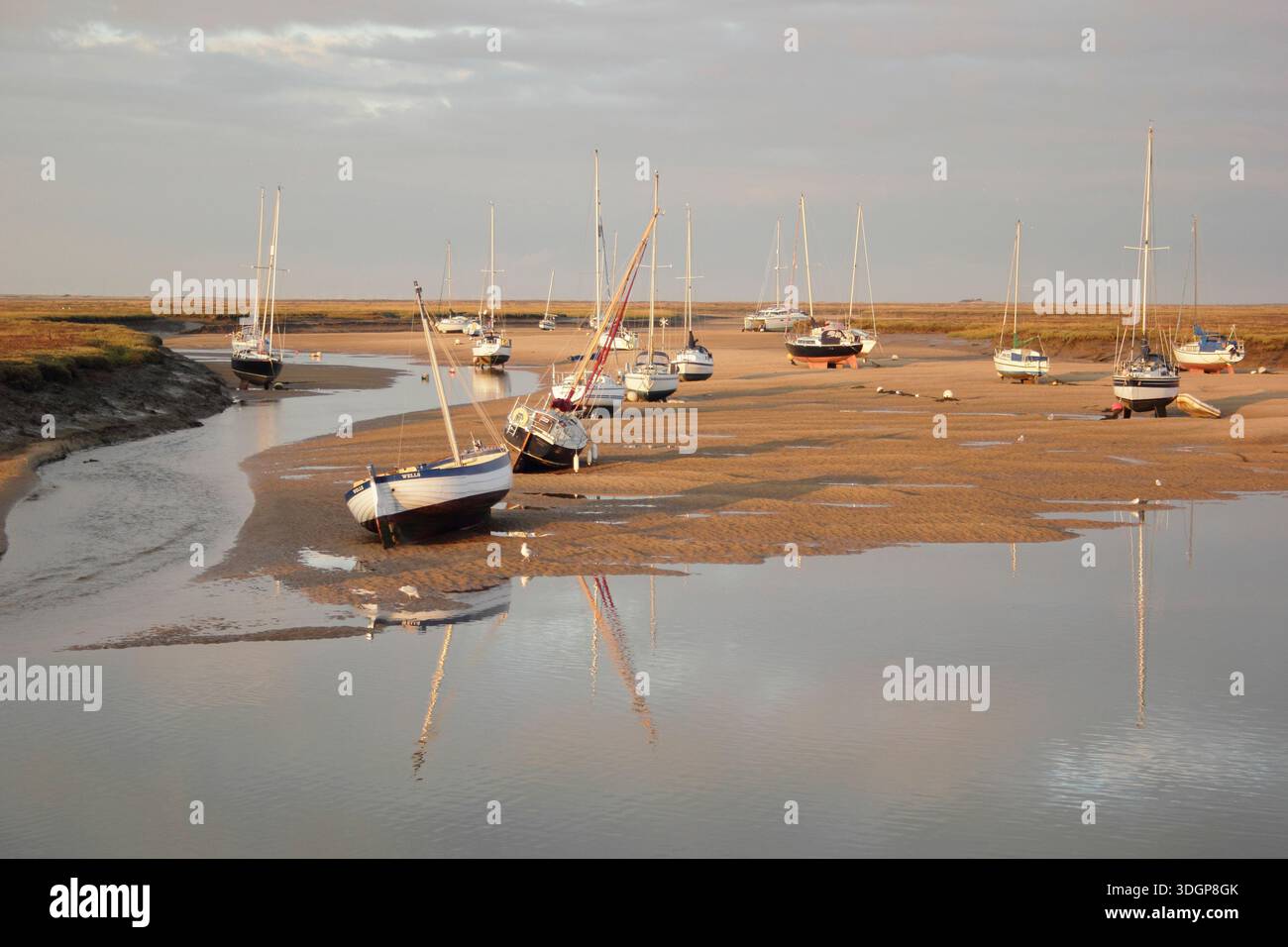 Puits à côté de la mer. Bateaux à marée basse dans le ruisseau du canal de sable à Wells à côté du port de mer, à la recherche de marais salants. North Norfolk, Angleterre, Grande-Bretagne Banque D'Images