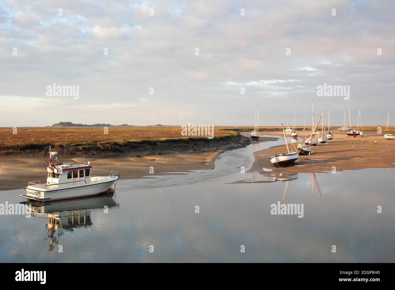 Puits à côté de la mer. Bateaux à marée basse dans le ruisseau du canal de sable à Wells à côté du port de mer, à la recherche de marais salants. North Norfolk, Angleterre, Grande-Bretagne Banque D'Images