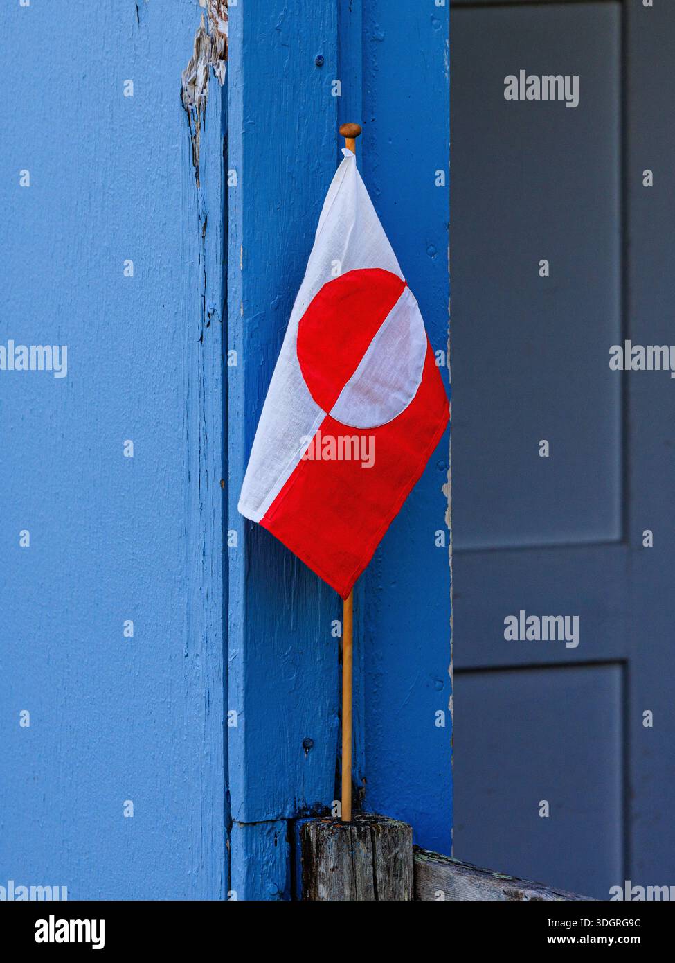 le drapeau rouge et blanc du groenland sur un petit mât de drapeau en bois se dresse dans une porte porche bleue pour accueillir les visiteurs Banque D'Images