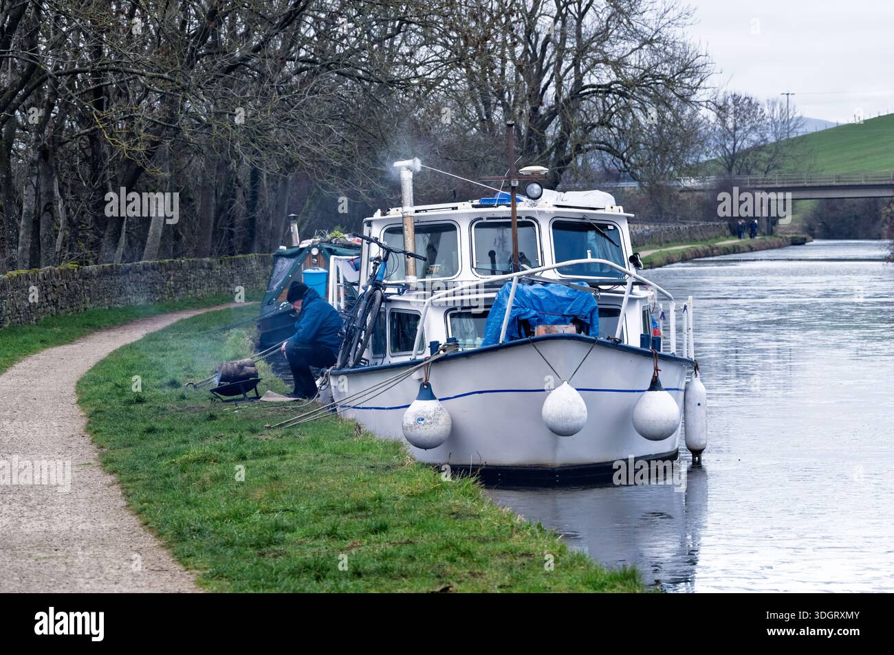 Garder au chaud sur un bateau de canal dans les eaux gelées du canal de Leeds Liverpool à Skipton. Une ville de marché et une paroisse civile dans le North Yorkshire, Angleterre Banque D'Images