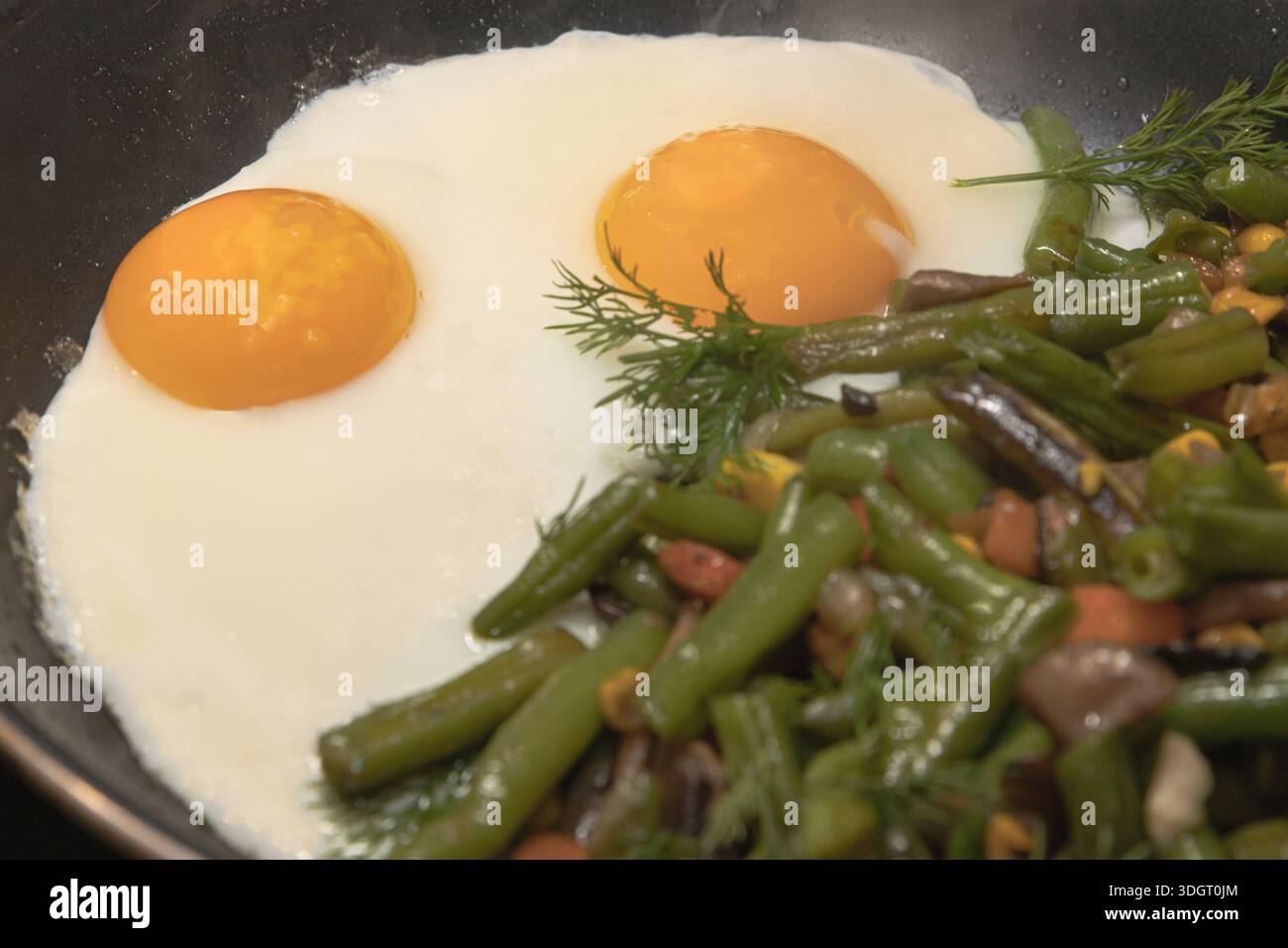 Oeufs frits avec mélange de légumes haricots verts champignons et herbes cuisant dans une poêle Banque D'Images