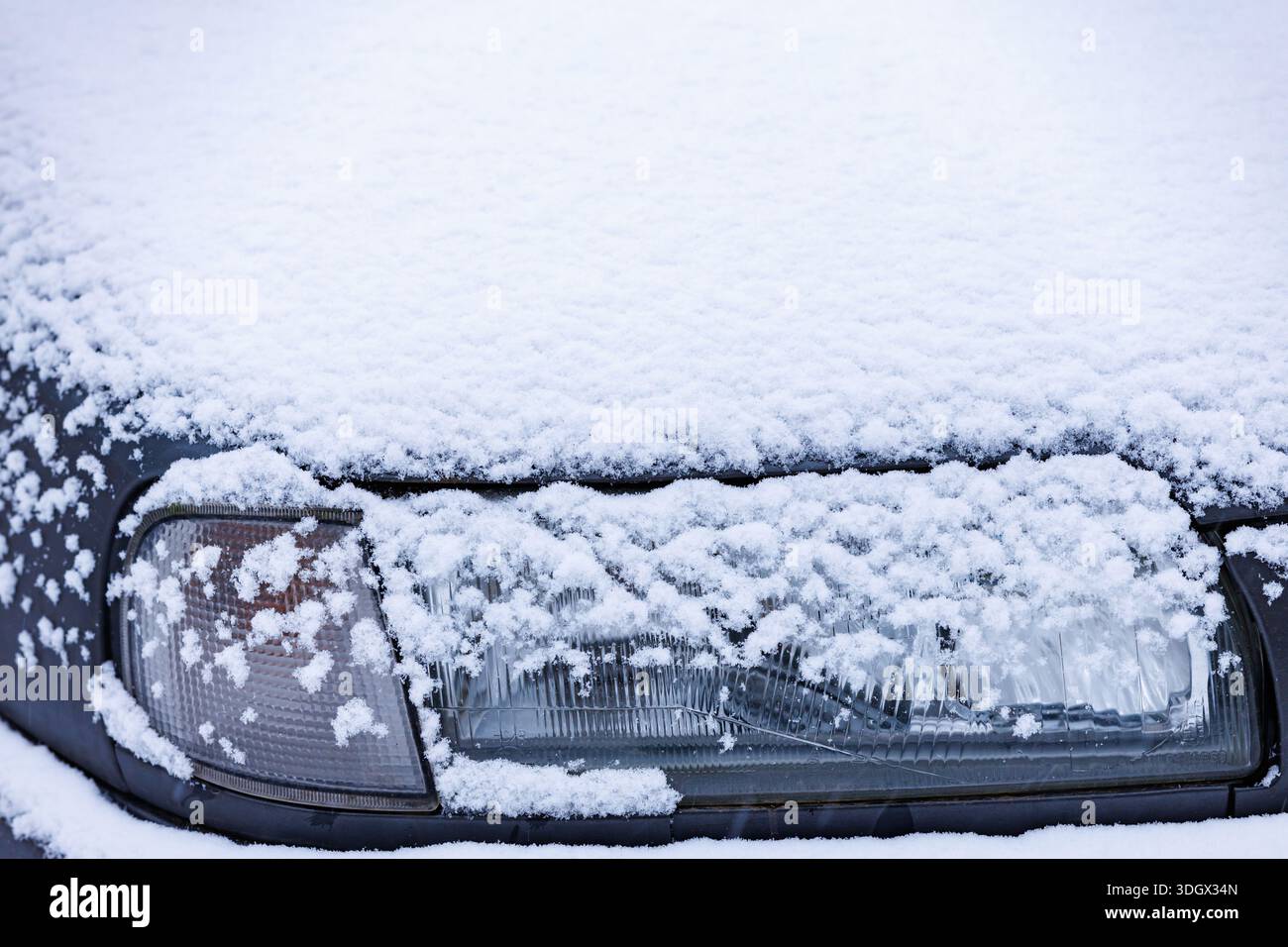 Phare de voiture recouvert de neige. Phare de voiture partiellement recouvert de neige fraîche, conduite hivernale et concept de sécurité par temps froid. Banque D'Images