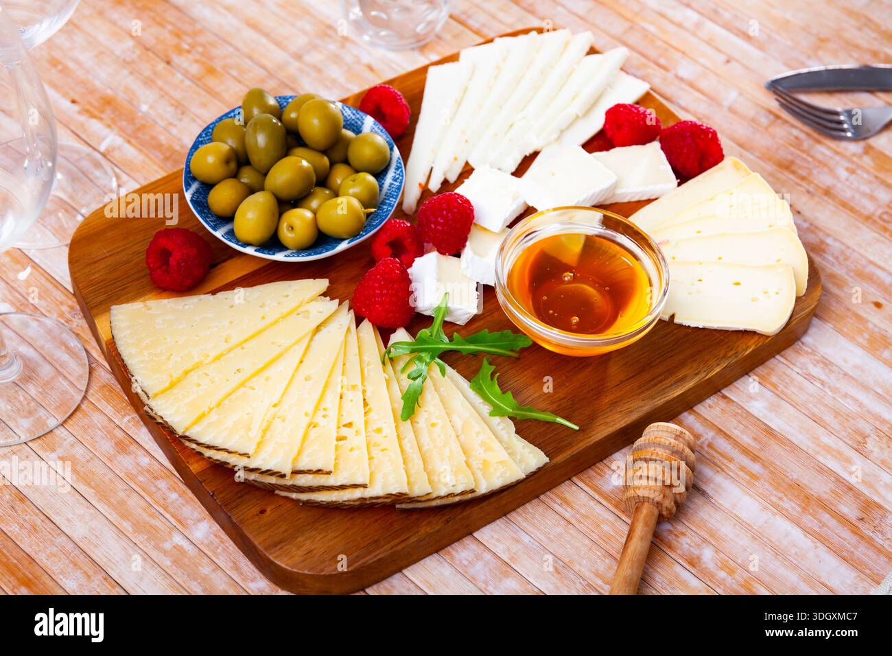 Différents types de fromage, miel, framboises et olives sur bois Banque D'Images