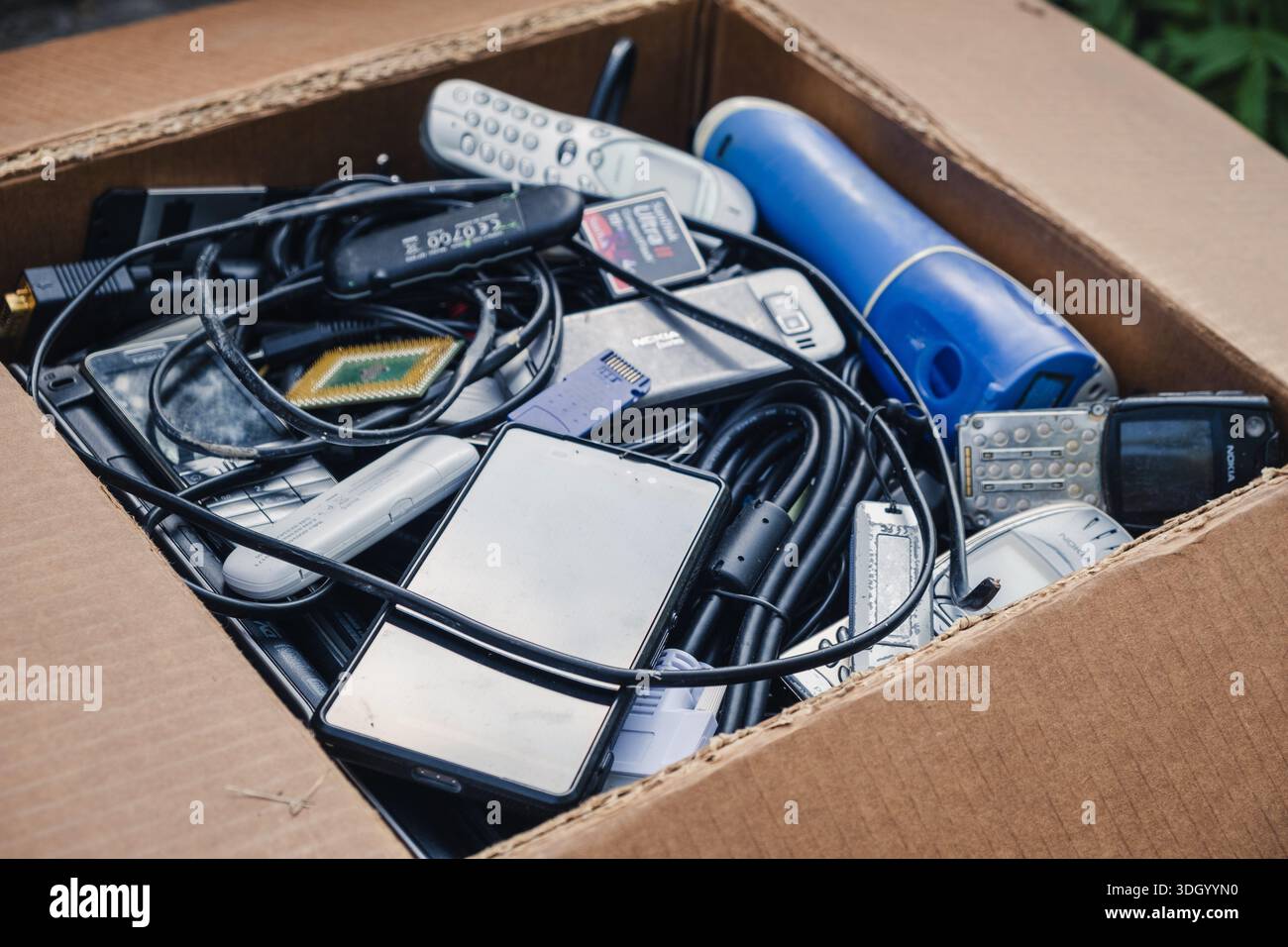 Boîte en carton remplie de déchets électroniques ménagers, vieux téléphones portables, smartphones, câbles enchevêtrés et un irrigateur buccal, préparé pour le recyclage à un e Banque D'Images