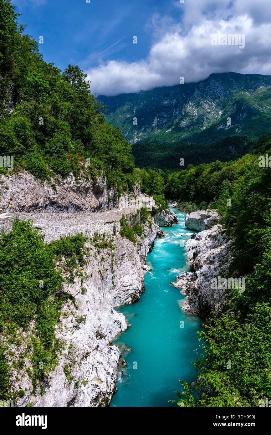 Vue en angle élevé de la rivière Soca turquoise qui coule à travers une gorge rocheuse, avec des montagnes escarpées sous les nuages au loin. Banque D'Images