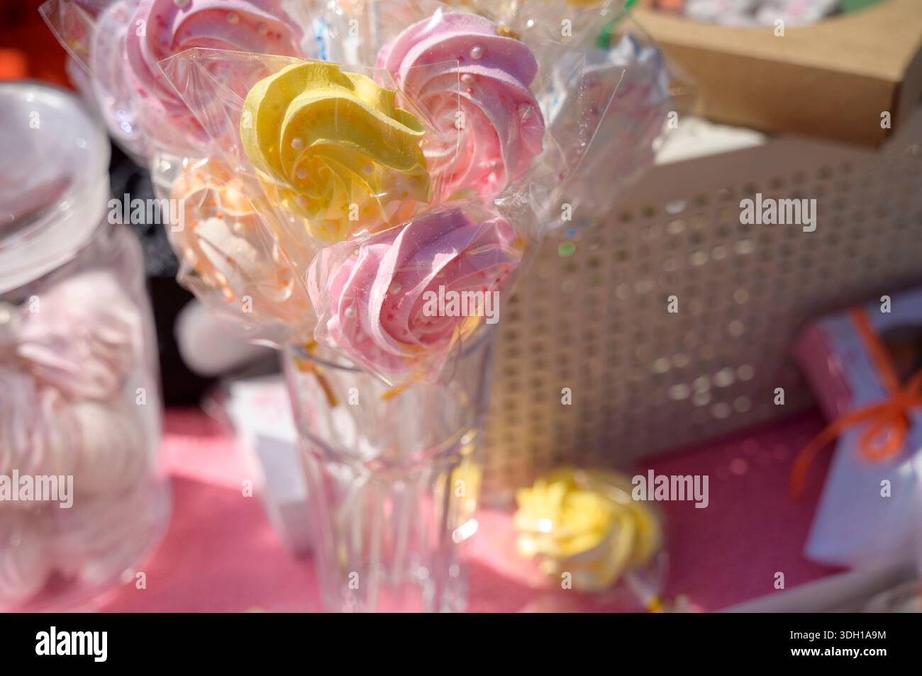 zephyr en forme de rose pastel fait à la main apparaît dans des emballages en plastique sur un marché. Concept de bonbons artisanaux, friandises festives de vacances, et foire colorée de printemps à Banque D'Images
