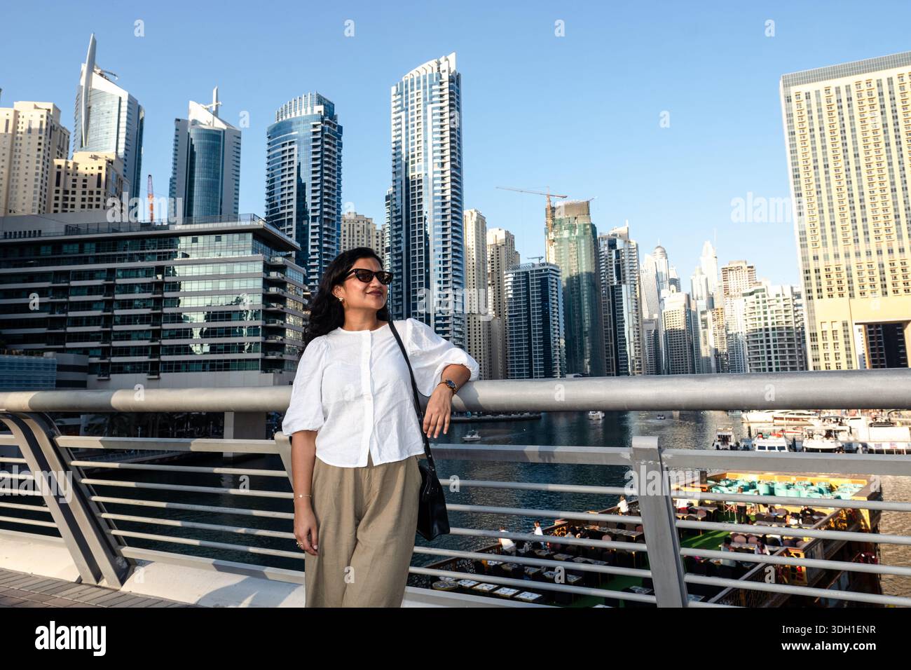 Femme confiante debout à Dubai Marina avec un horizon moderne et un style de vie urbain, voyage et style de vie à Dubaï - photo stock Banque D'Images