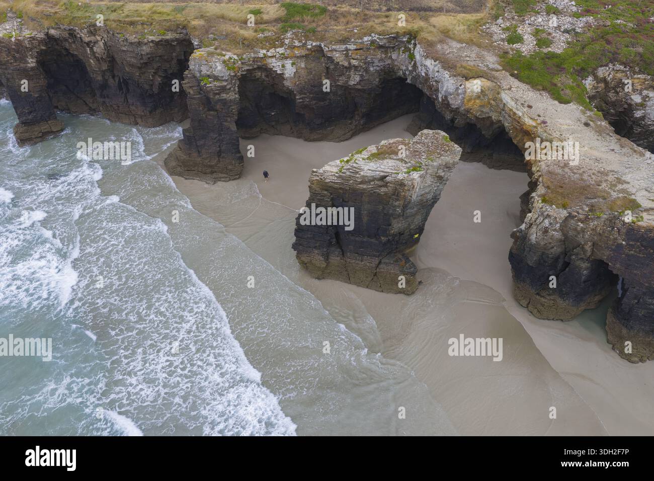 Vue aérienne de la côte accidentée où le sable doré rencontre la mer turquoise sous l'ombre des formations rocheuses spectaculaires, Ribadeo, Galice, Banque D'Images