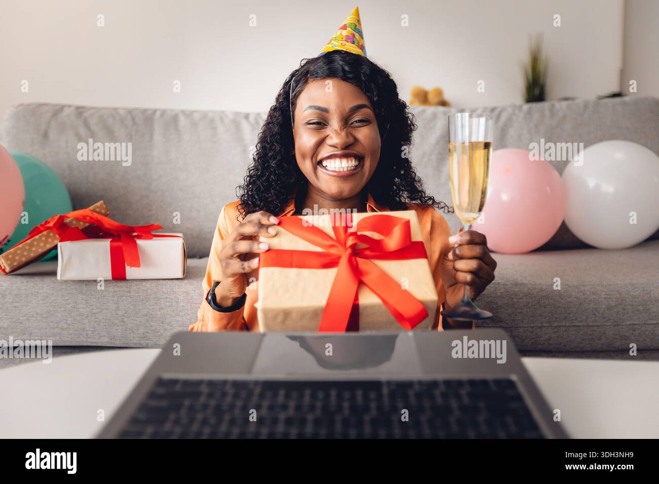 Vue de face d'une femme noire offrant un cadeau d'anniversaire à un ordinateur portable à l'intérieur Banque D'Images