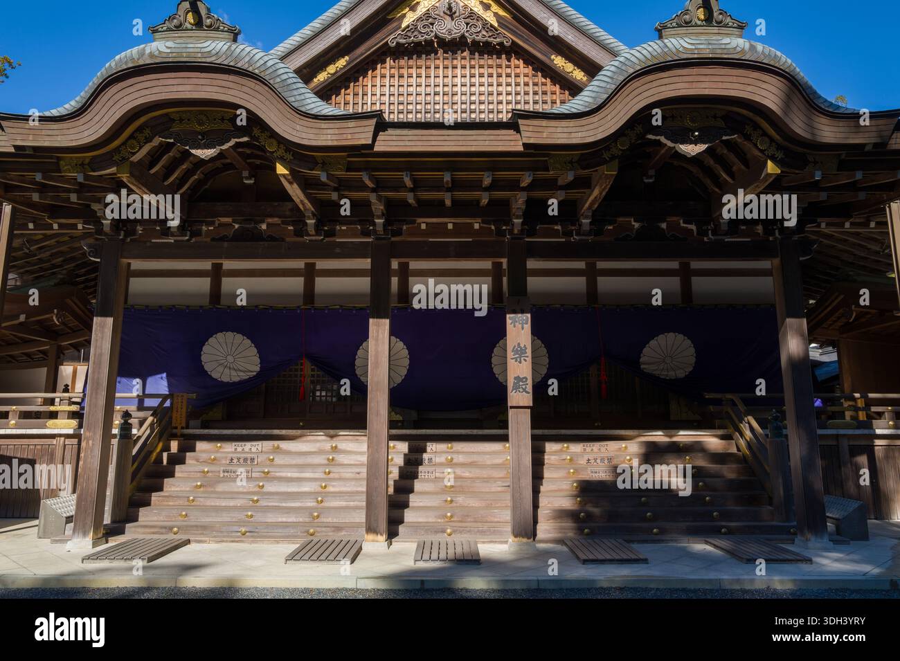 ISE, Japon - 29 octobre 2023 : la façade avant de la salle Kaguraden à ISE Jingu est représentée avec une architecture traditionnelle en bois, des détails de toit ornés et des draperies violettes avec des emblèmes blancs au-dessus des marches d'entrée. Banque D'Images