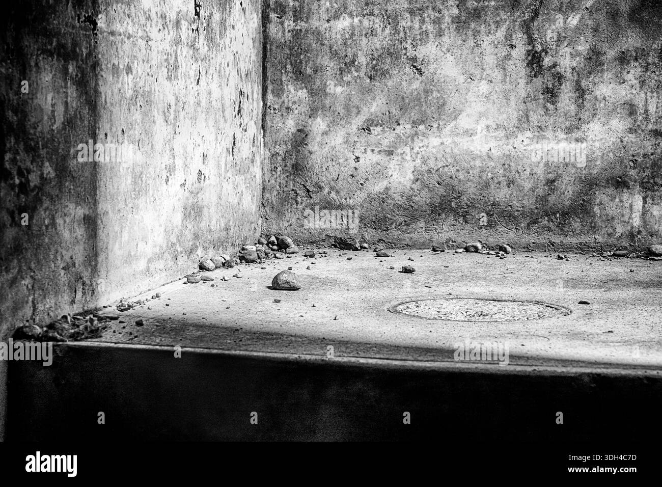 Une petite scène tranquille montrant de petits rochers et d'autres débris qui tapissent le bas d'un escalier à Fort Casey, Washington. En noir et blanc. Banque D'Images