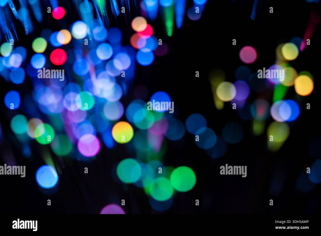 Un affichage captivant de lumières à fibre optique multicolores éclatantes créant un effet bokeh époustouflant sur fond noir. Le motif abstrait est mesm Banque D'Images
