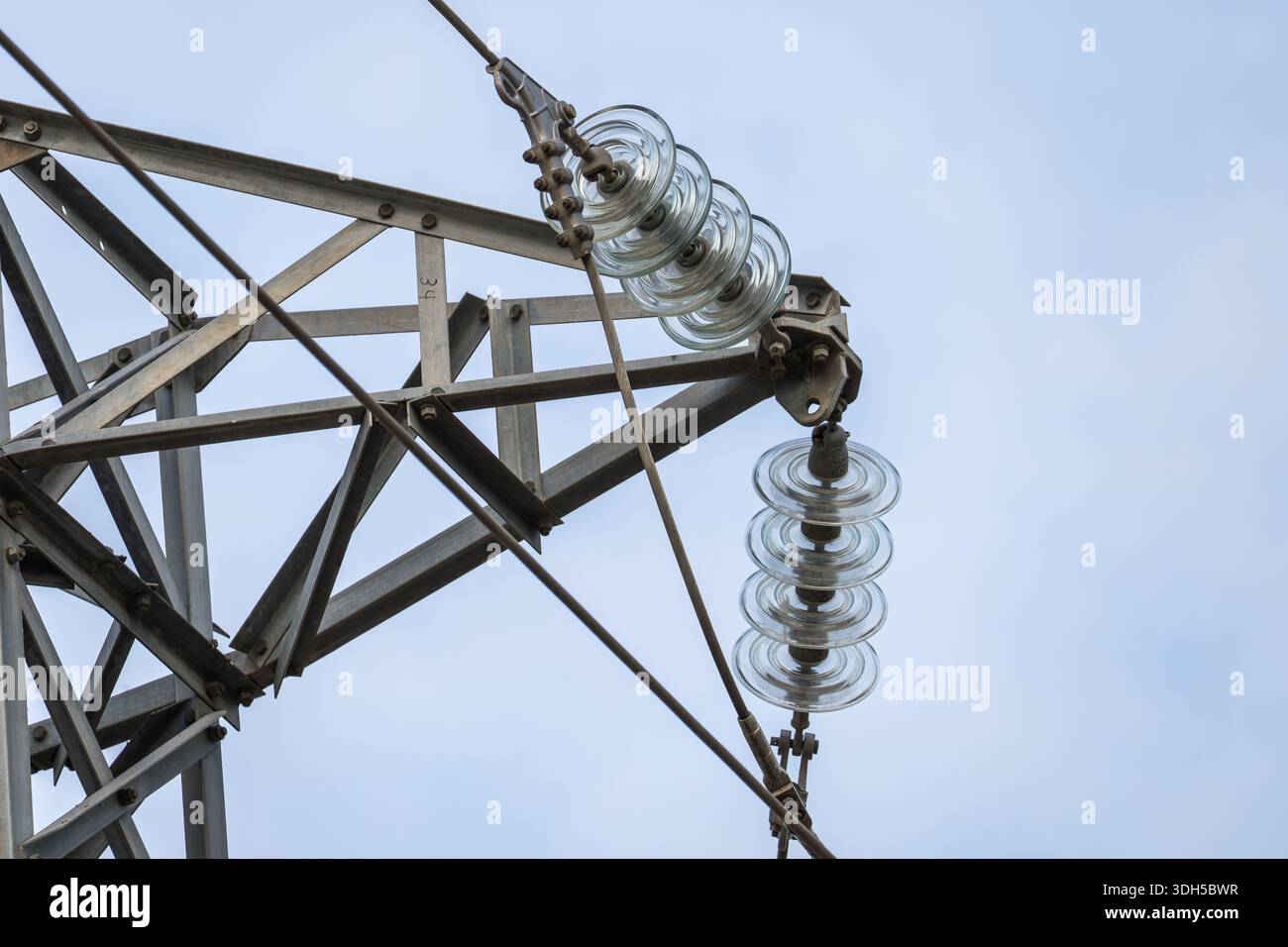 Gros plan de la structure en acier et des isolateurs de verre d'une centrale électrique contre un ciel dégagé. La structure met en évidence la complexité et la force de l'électr Banque D'Images