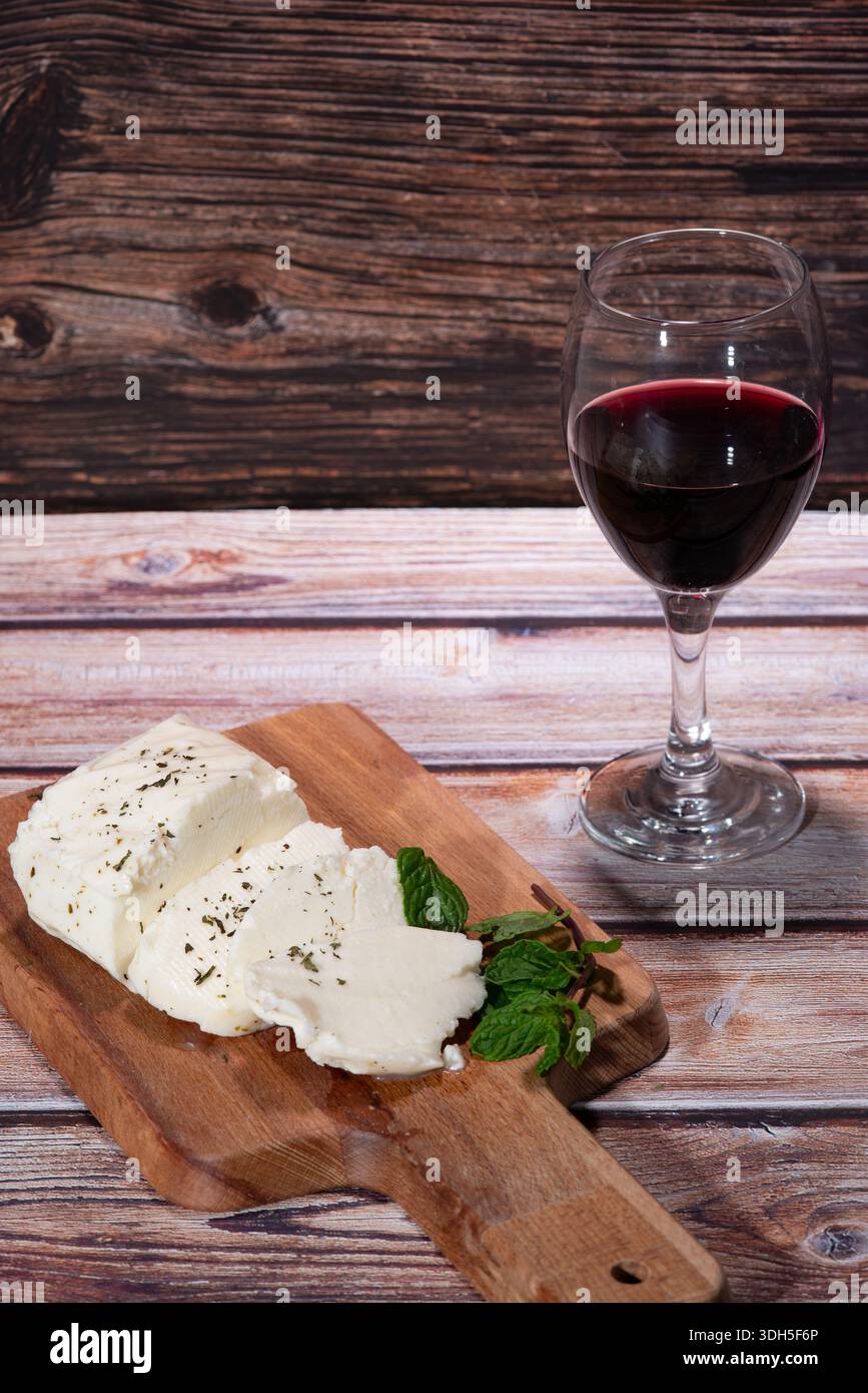 Plateau traditionnel de fromage halloumi, raisins et vin rouge sur une planche de bois. Le halloumi fait partie du régime méditerranéen Banque D'Images