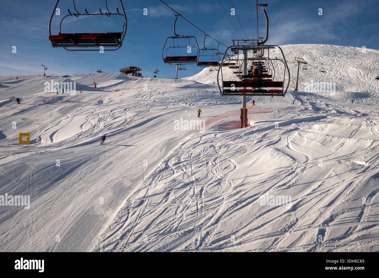 Station de ski ensoleillée transportant des skieurs sur une pente enneigée sous un ciel bleu éclatant dans les Alpes françaises du 20 au 26 janvier, vacances de vacances Banque D'Images