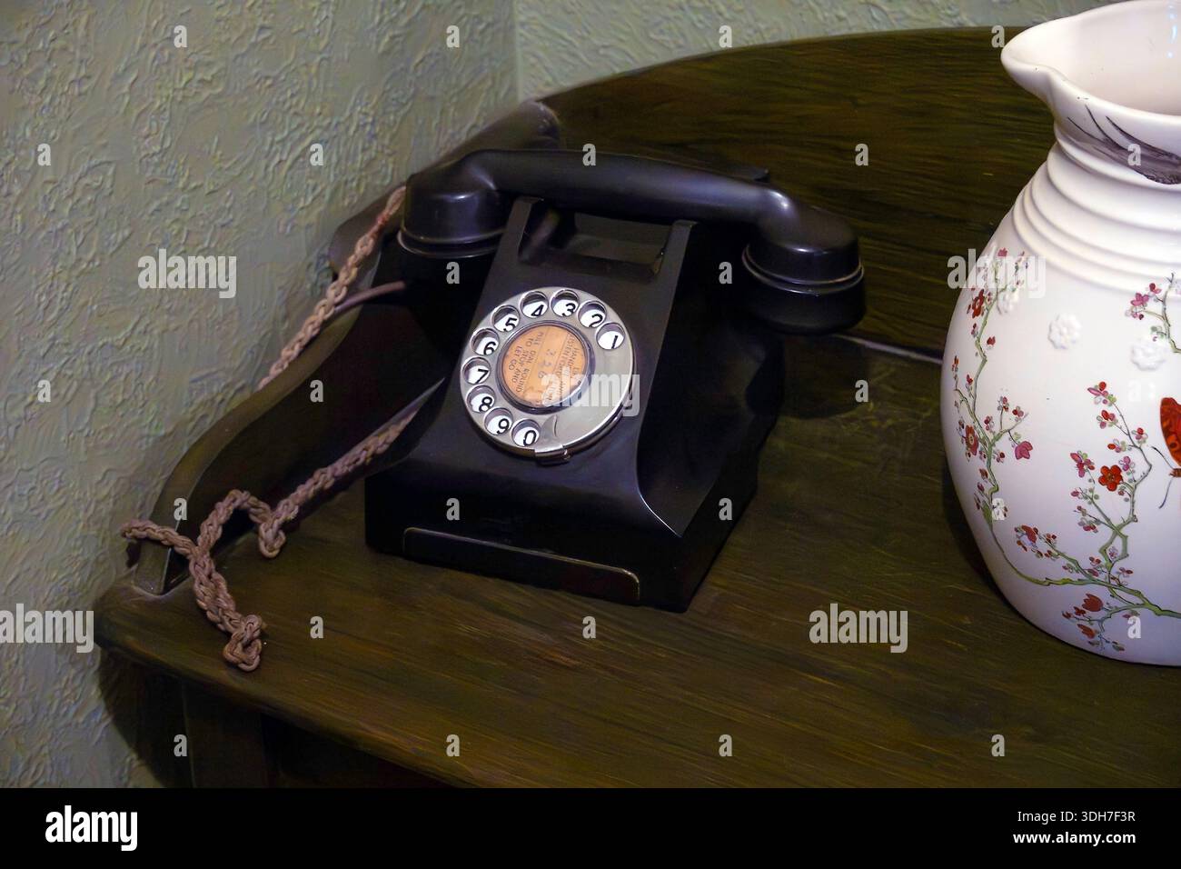 Téléphone à cadran rotatif vintage sur le bureau en bois avec vase Banque D'Images