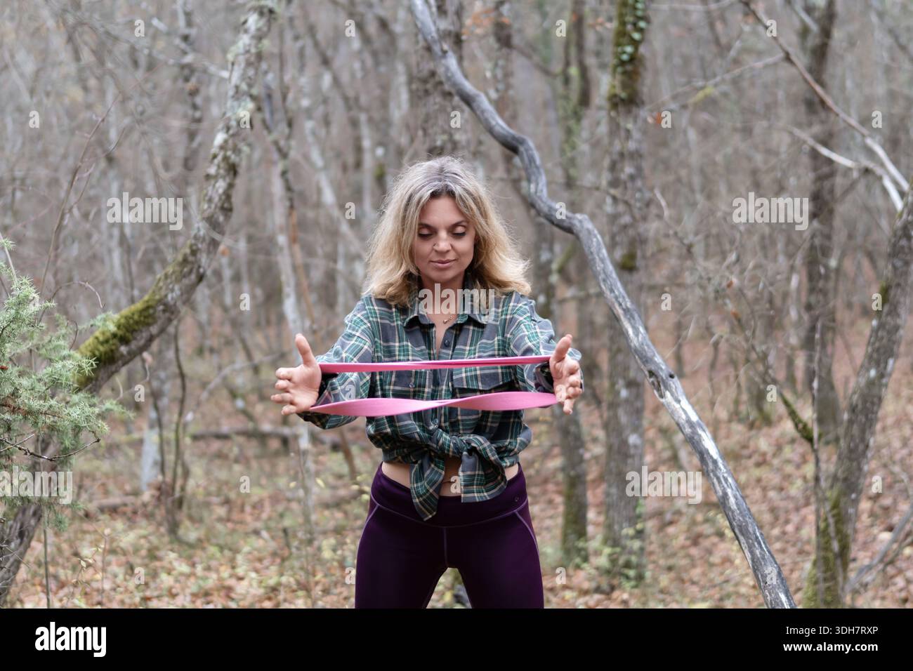 Femme exercice bande de résistance à l'extérieur dans le cadre boisé de forêt d'automne Banque D'Images