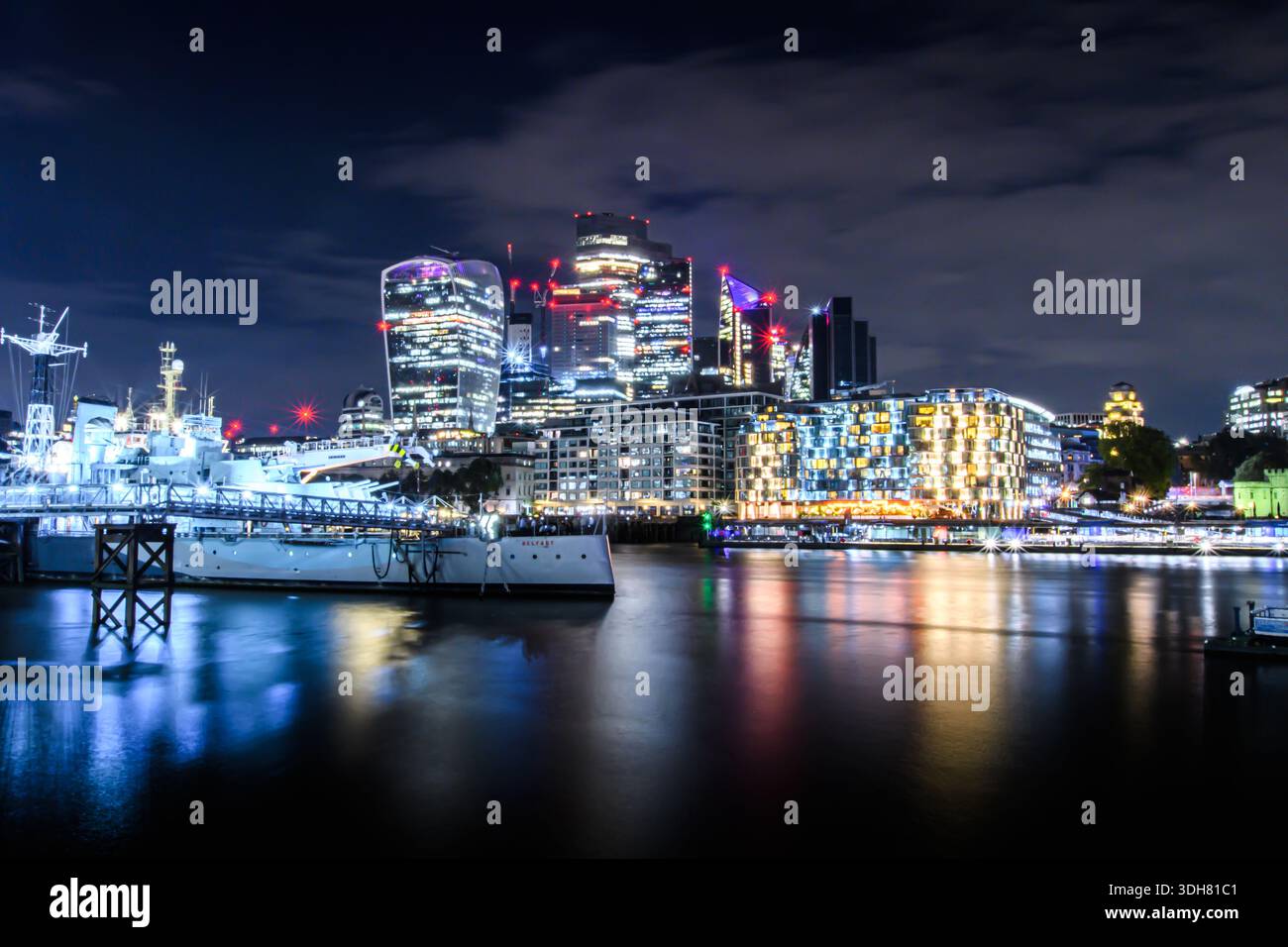 Vue nocturne sur les gratte-ciel de Londres avec des bâtiments modernes illuminés reflétant la Tamise. Banque D'Images