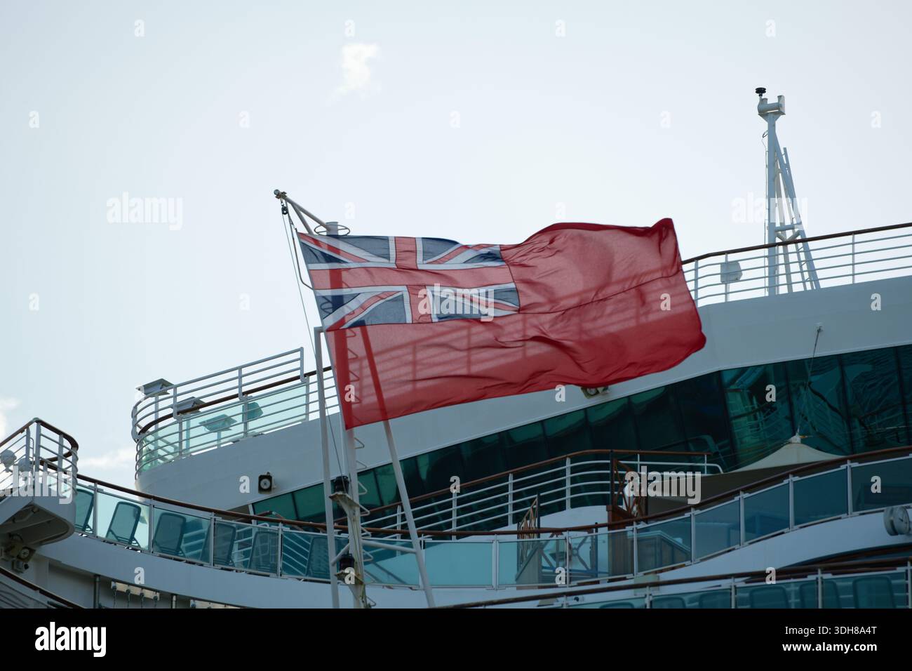 L'enseigne rouge s'envole de l'arrière d'un bateau de croisière. Banque D'Images