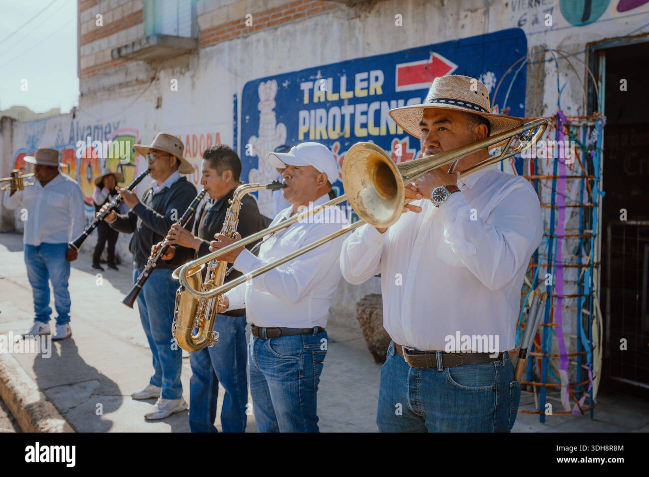 Un groupe de musiciens jouent des instruments à vent comme des trombones et des clarinettes devant un atelier de pyrotechnie lors d'un festival culturel traditionnel Banque D'Images