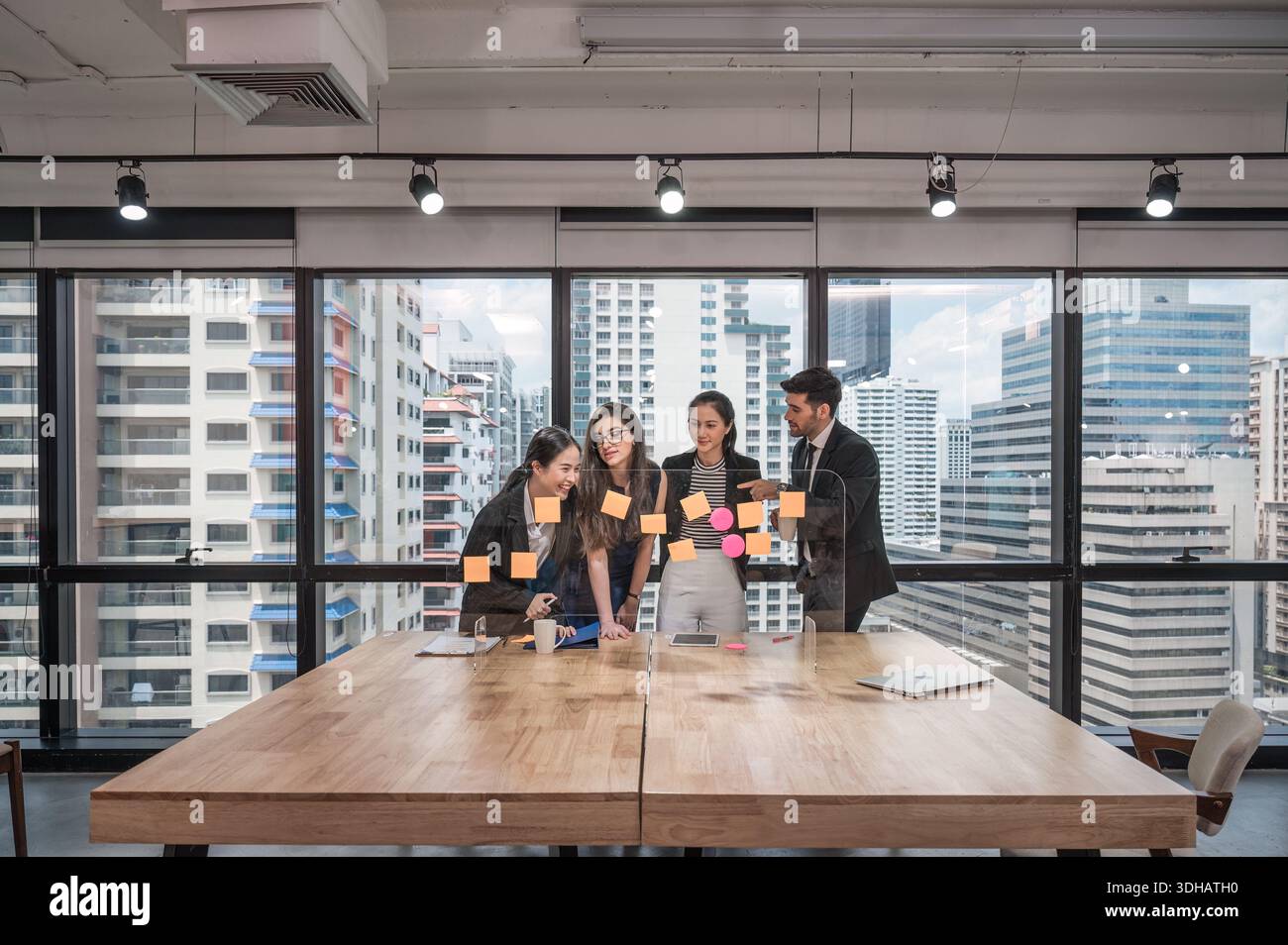 Groupe de collègues d'affaires multiethniques analysant et discutant de l'idée de projet d'entreprise avec la note collante collée à bord dans le bureau moderne Banque D'Images