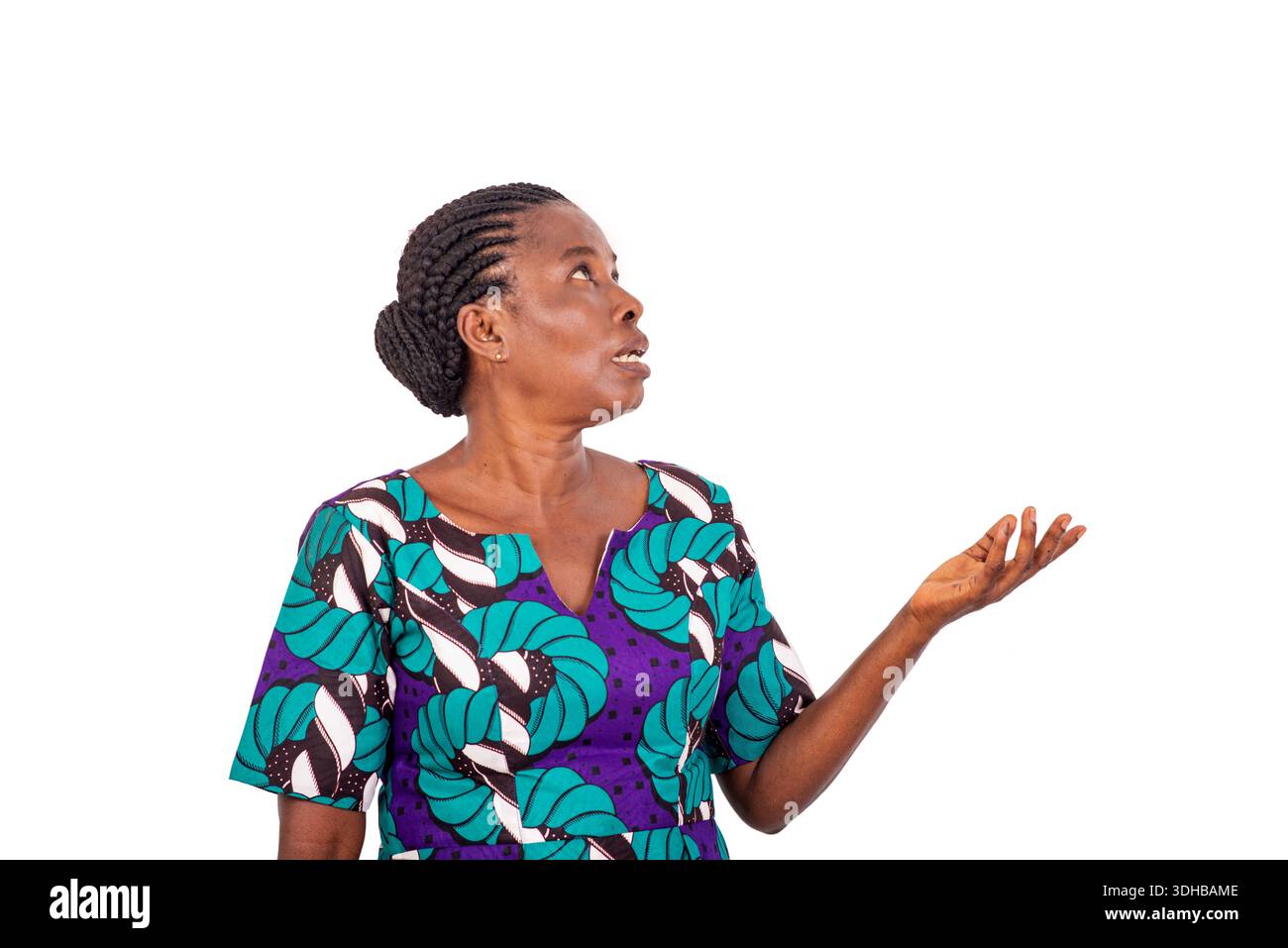 Belle femme africaine en robe de pagne debout sur fond blanc regardant là-haut tout en parlant. Banque D'Images