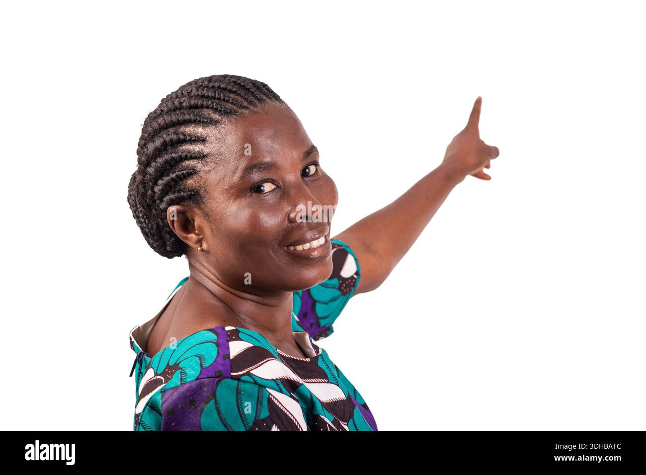 belle femme africaine en robe de pagne debout sur fond blanc montrant la direction en pointant l'index tout en souriant. Banque D'Images