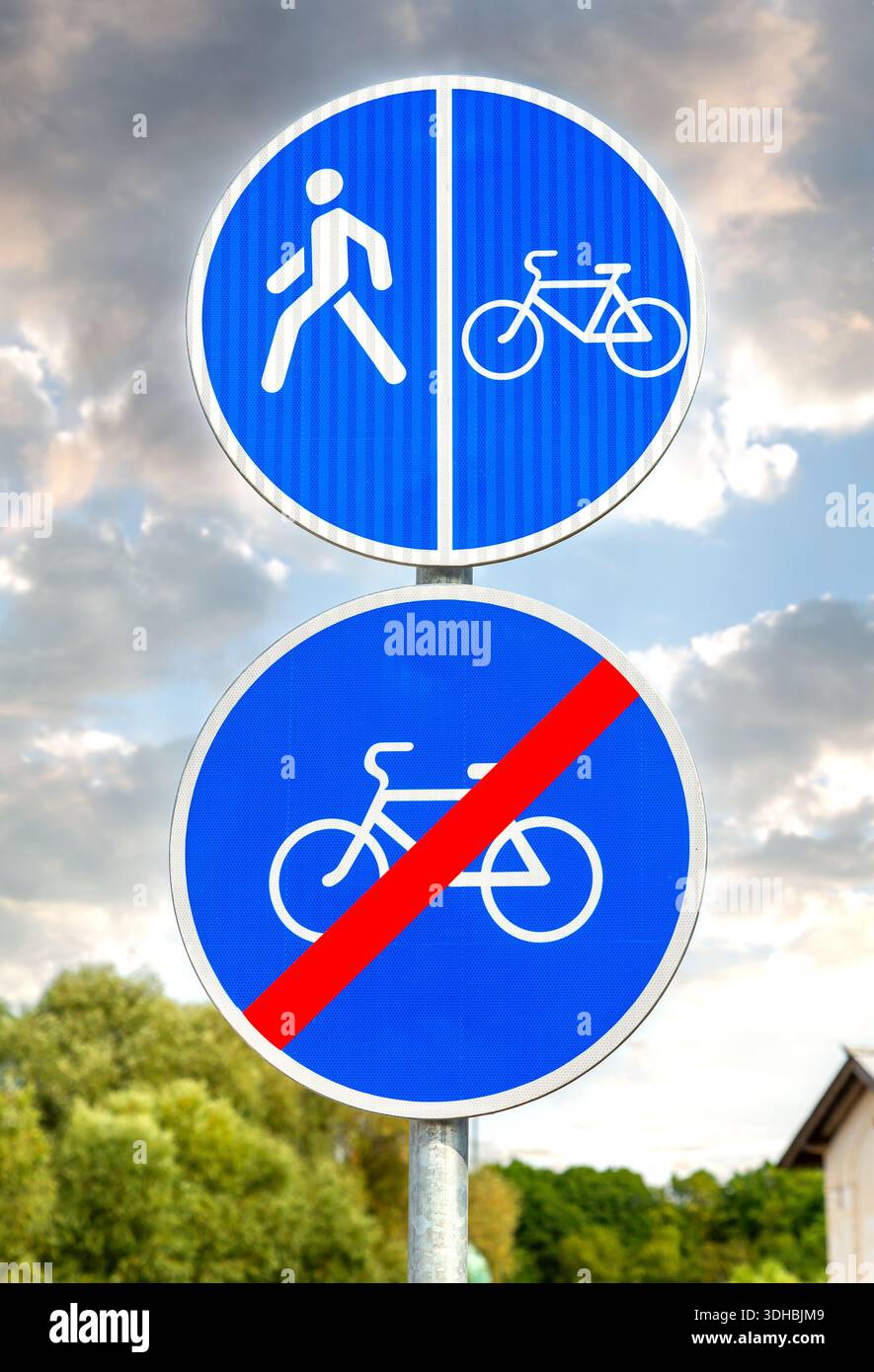 Panneaux routiers 'piste piétonne et cyclable' et 'pas de vélos' contre le ciel bleu nuageux Banque D'Images